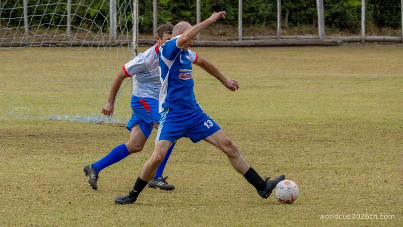 Soccer player in blue uniform kicking ball on a field.